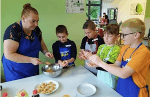 Vier Schüler und eine Lehrerin, die Hackbällchen formen.