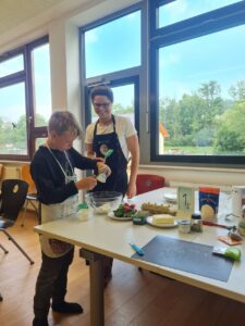 Ein Schüler und eine Lehrerin, die Zutaten für den Radieschen-Kresse-Quark in eine Schüssel füllen.