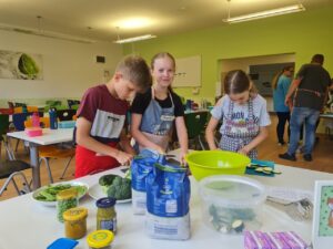 Drei Schüler, die die grüne Pesto-Pasta machen.